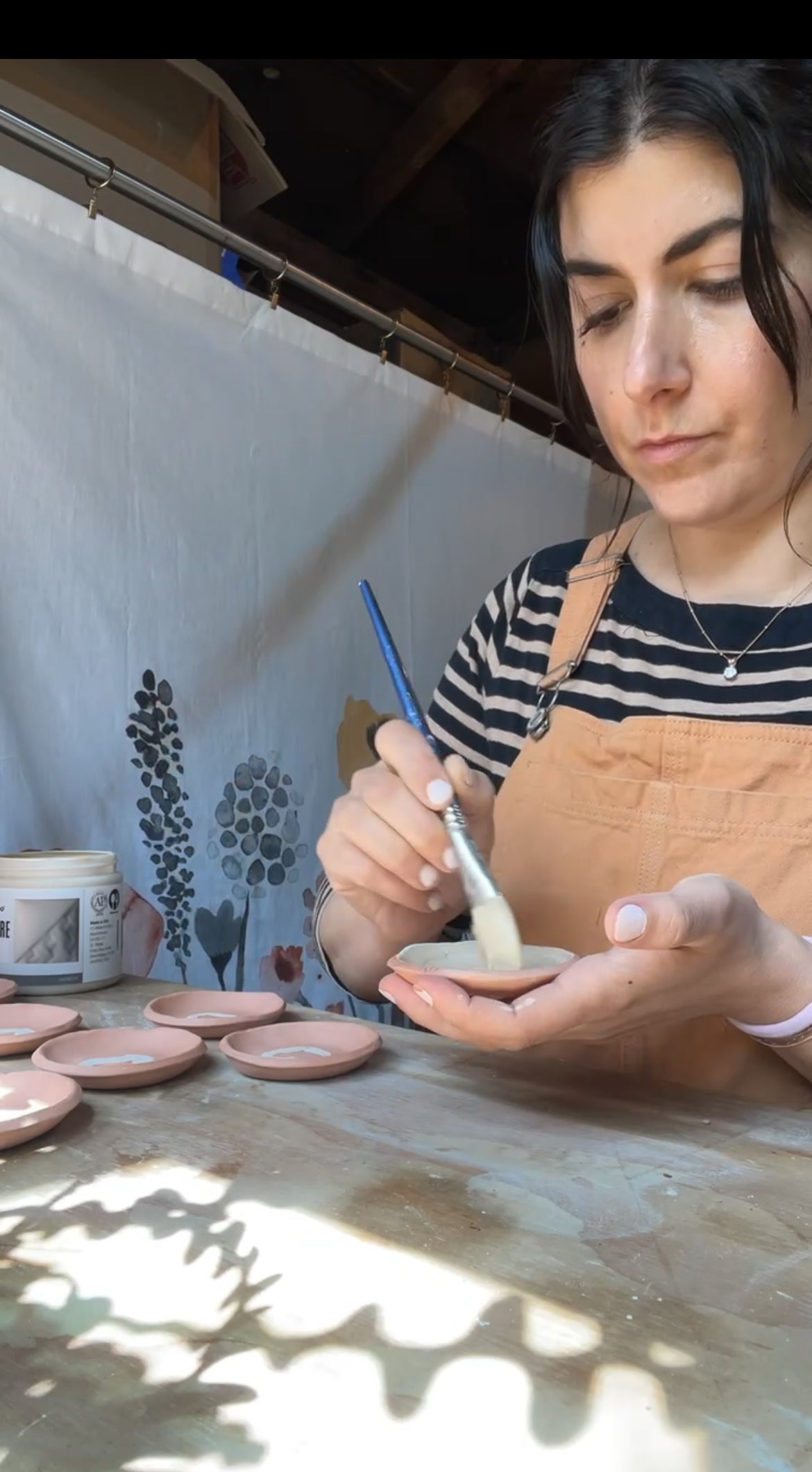 person holding bisque ware pottery and glazing the ceramics