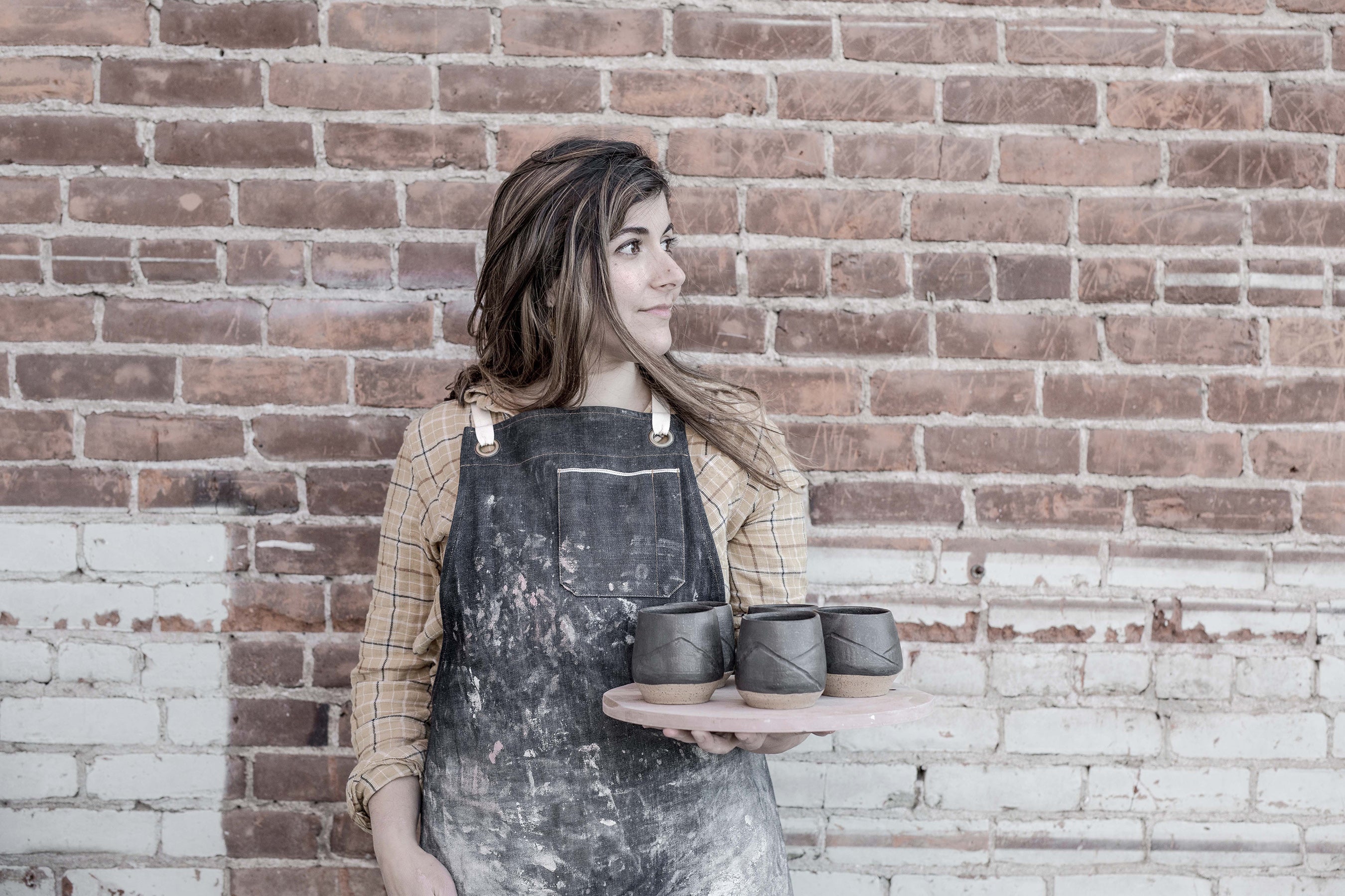 Luma holding in progress mugs in her ceramic studio in central oregon